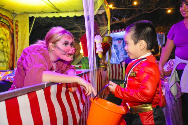Nicole Truex, dressed as a carnival freak named Pig Girl, hands out candy to a trick-or-treater at The District on Halloween night Monday, Oct. 31, 2011.